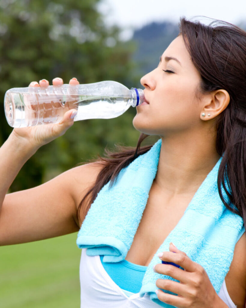 woman drinking water from a plastic bottle